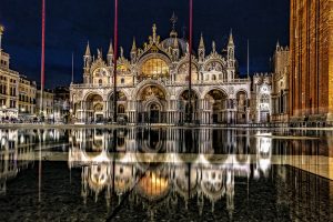 Foto nocturna de la Basílica de San Marcos con el suelo mojado