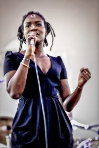 Medio cuerpo de la cantante de Cosmosoul con el micro en la mano