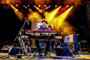 Plano abierto del escenario con Josh Hoyer en el centro tocando el teclado